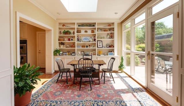 dining room with a skylight, light wood-style floors, ornamental molding, and built in shelves