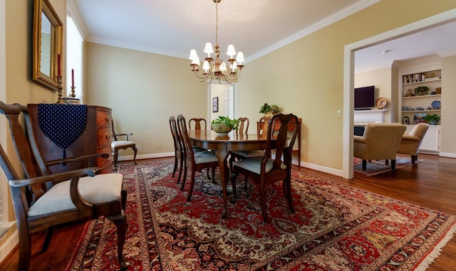 dining area with wood finished floors, crown molding, a chandelier, baseboards, and built in features