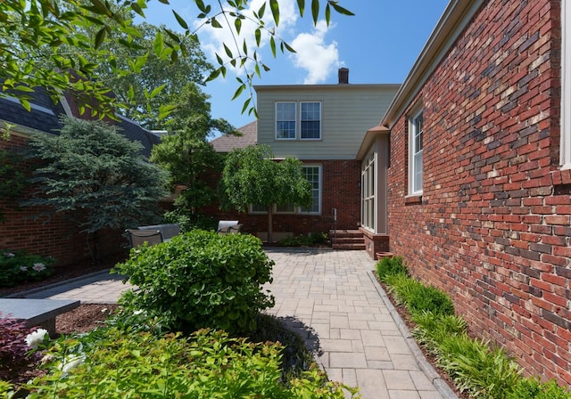 property entrance featuring brick siding, a chimney, and a patio area