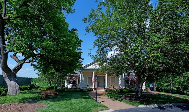 view of property hidden behind natural elements with a porch and a front lawn