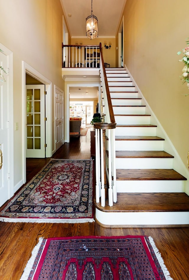 foyer with stairs, a high ceiling, a chandelier, and wood finished floors