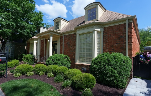 view of side of property with brick siding and a shingled roof