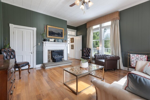 3310 Booker Ridge Rd, Mount Pleasant, TN 38474 - living area featuring wood finished floors, a fireplace with raised hearth, crown molding, a ceiling fan, and baseboards