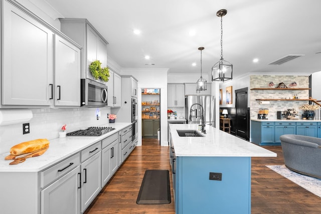 kitchen with stainless steel appliances, decorative backsplash, a sink, ornamental molding, and a center island with sink