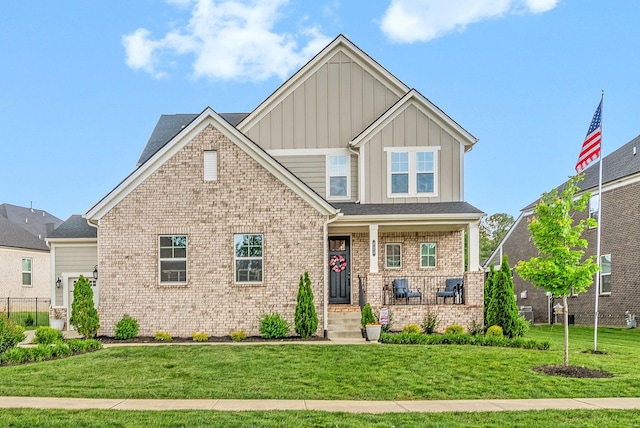 craftsman-style house with board and batten siding, covered porch, a front yard, and brick siding