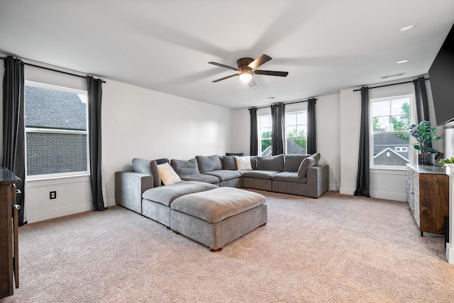 living area featuring a ceiling fan, light carpet, and baseboards