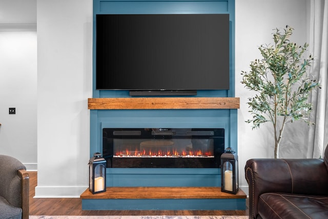 detailed view of a large fireplace, wood finished floors, and baseboards