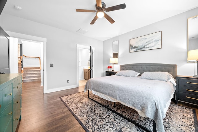bedroom featuring wood finished floors, baseboards, ceiling fan, and ensuite bath