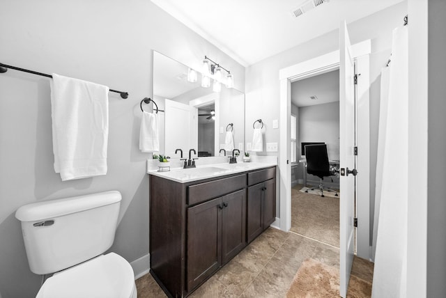 full bathroom with toilet, double vanity, and baseboards