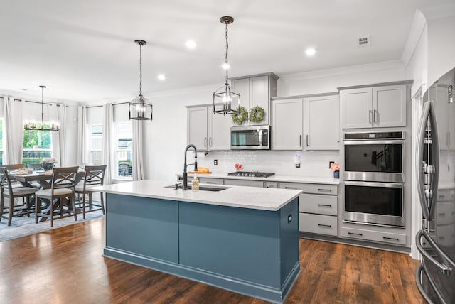 kitchen with a sink, stainless steel appliances, tasteful backsplash, gray cabinets, and a kitchen island with sink