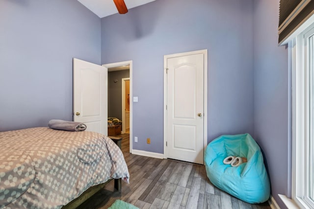 bedroom featuring wood finished floors, baseboards, and a towering ceiling