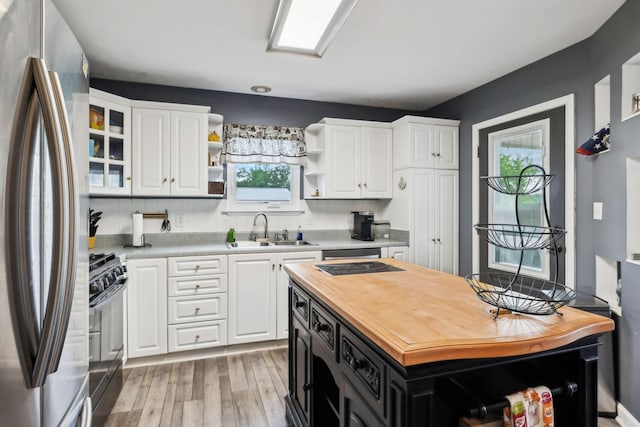 kitchen with black appliances, a sink, open shelves, and healthy amount of natural light