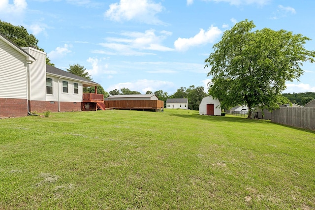 view of yard featuring a shed, an outdoor structure, and a deck