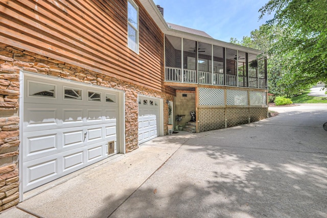 114 Moonlight Dr, Gallatin, TN 37066 - view of home's exterior featuring a sunroom, stone siding, driveway, an attached garage, and a ceiling fan