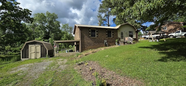 10172 W Oak Dr, Bon Aqua, TN 37025 - rear view of house featuring a storage shed, brick siding, a lawn, and an outdoor structure