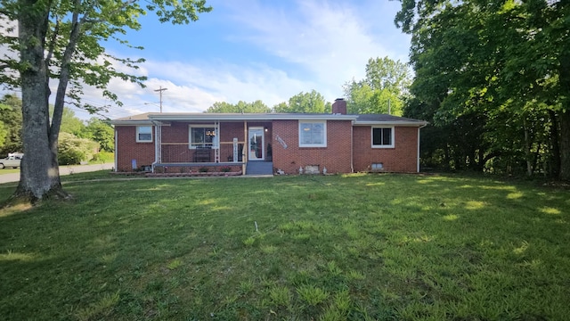back of property featuring a yard, brick siding, and a chimney