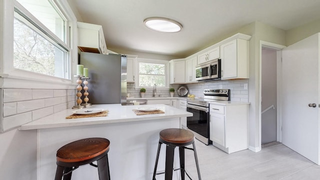 1304 Cheshire Dr, Nashville, TN 37207 - kitchen featuring appliances with stainless steel finishes, a kitchen breakfast bar, a peninsula, and decorative backsplash