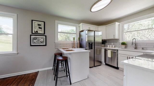 1304 Cheshire Dr, Nashville, TN 37207 - kitchen featuring appliances with stainless steel finishes, a sink, a kitchen breakfast bar, backsplash, and white cabinetry