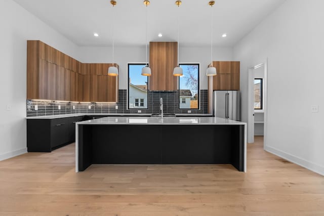 kitchen featuring modern cabinets, freestanding refrigerator, brown cabinets, light countertops, and recessed lighting