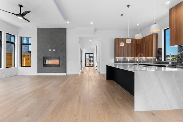 kitchen with modern cabinets, brown cabinetry, a sink, light wood-type flooring, and a ceiling fan