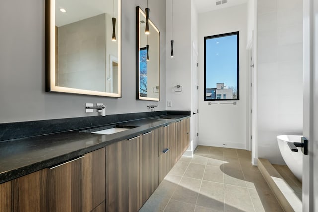 bathroom featuring a soaking tub, tile patterned floors, double vanity, baseboards, and healthy amount of natural light