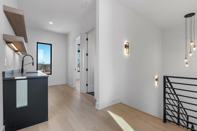 corridor featuring a sink, light wood-style floors, baseboards, and recessed lighting