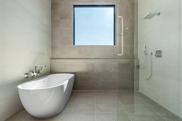 bathroom with tiled shower, a soaking tub, and tile walls