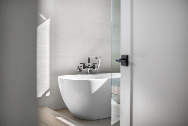 bathroom with tile walls, a freestanding tub, and decorative backsplash