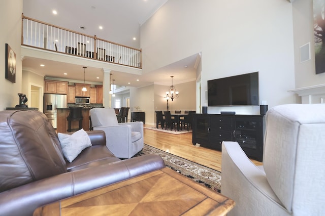 1005 Peck Pl, Hendersonville, TN 37075 - living room featuring a towering ceiling, ornamental molding, light wood finished floors, a chandelier, and decorative columns