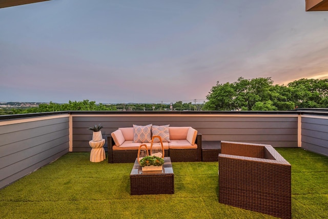 patio terrace at dusk featuring an outdoor living space, a balcony, and a yard