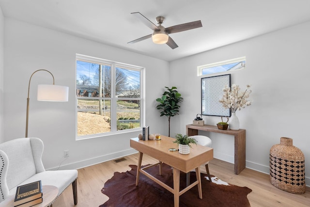 office featuring plenty of natural light, a ceiling fan, baseboards, and light wood finished floors