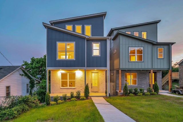 contemporary house with board and batten siding, a front yard, and stairs