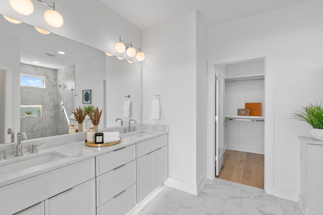 full bathroom with a marble finish shower, marble look tiles, double vanity, and baseboards