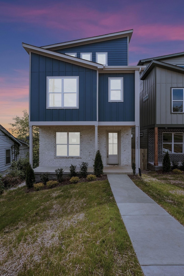 view of front of property with board and batten siding, a front lawn, and covered porch