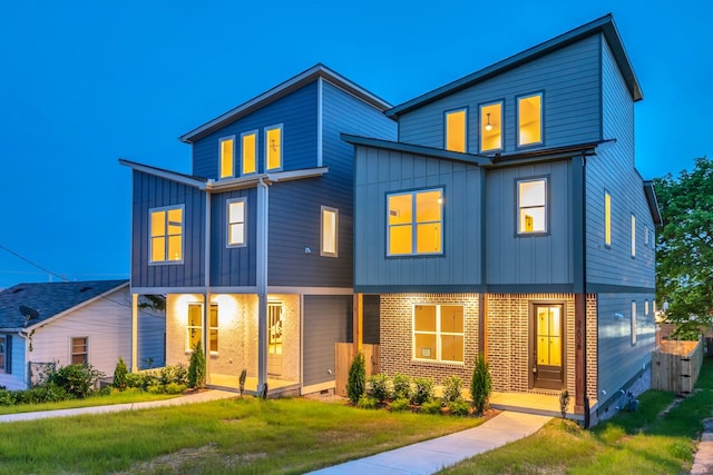 view of front of house featuring board and batten siding, a front lawn, and brick siding