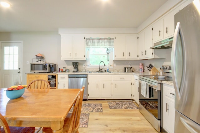 2878 Gusty Ln, Clarksville, TN 37043 - kitchen with appliances with stainless steel finishes, a sink, under cabinet range hood, light wood-type flooring, and light countertops