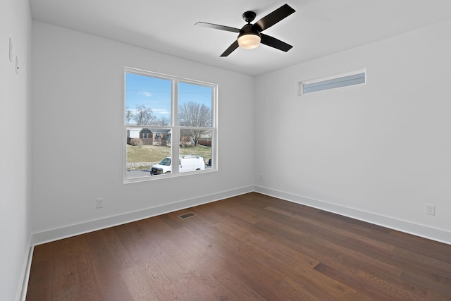 empty room featuring a ceiling fan, dark wood finished floors, and baseboards