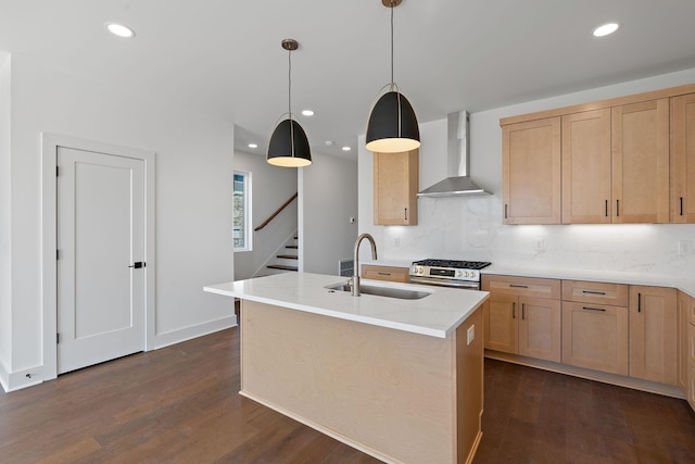 kitchen with wall chimney range hood, a sink, light brown cabinetry, stainless steel range with gas stovetop, and dark wood-style flooring