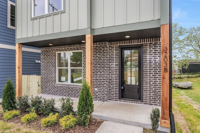 view of exterior entry featuring brick siding and board and batten siding