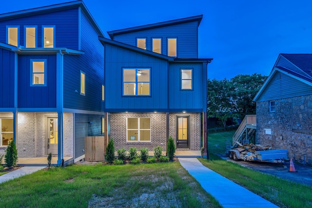 view of front of house featuring board and batten siding, stairway, brick siding, and a front yard