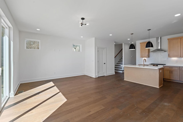 kitchen featuring wall chimney exhaust hood, healthy amount of natural light, dark wood-style flooring, light countertops, and recessed lighting