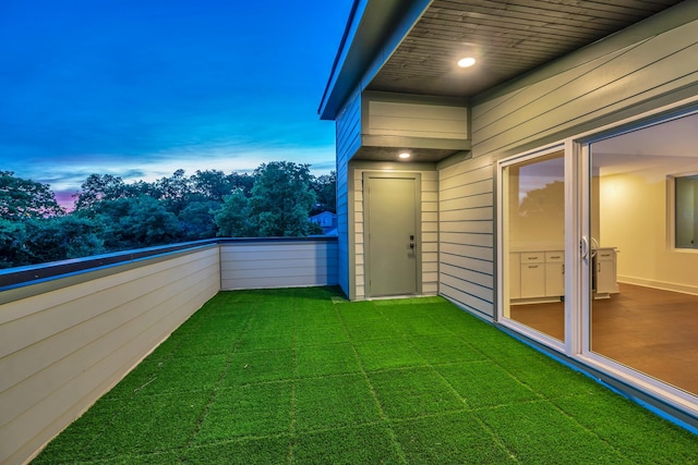 yard at dusk with a lawn and a balcony