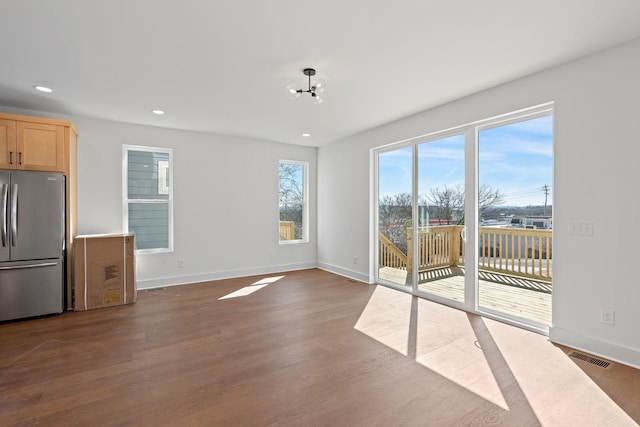 unfurnished living room with dark wood finished floors, recessed lighting, baseboards, and a chandelier