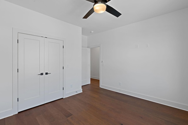 unfurnished bedroom featuring dark wood finished floors, baseboards, a closet, and a ceiling fan