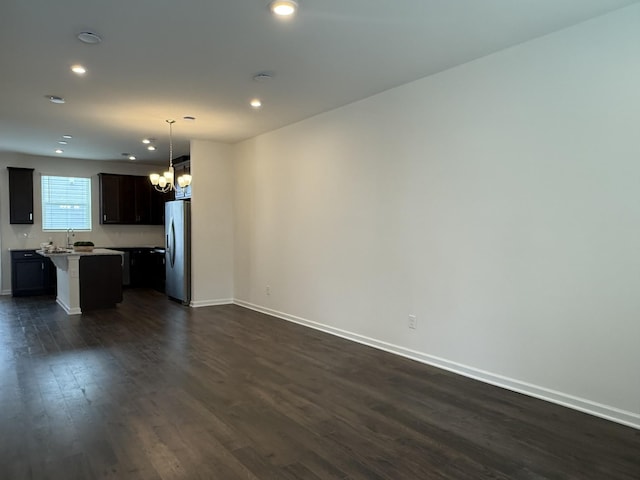 unfurnished living room featuring a chandelier, dark wood-style floors, baseboards, and recessed lighting