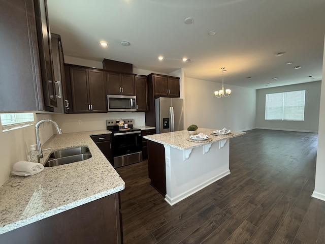 kitchen with appliances with stainless steel finishes, a sink, dark brown cabinets, dark wood-style flooring, and recessed lighting