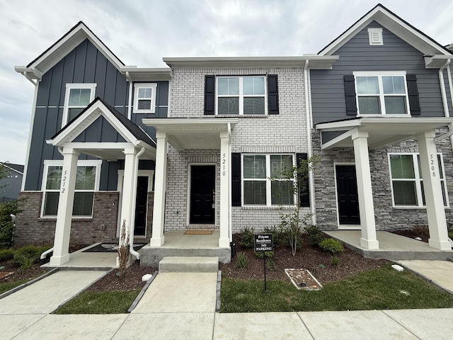 view of front of property featuring board and batten siding, brick siding, and covered porch