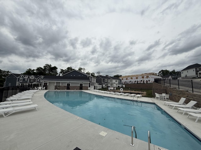 community pool with fence, a patio area, and a residential view