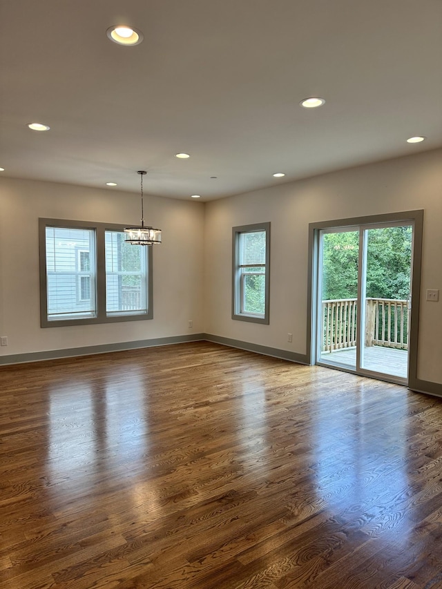 spare room with a chandelier, recessed lighting, baseboards, and dark wood-style flooring