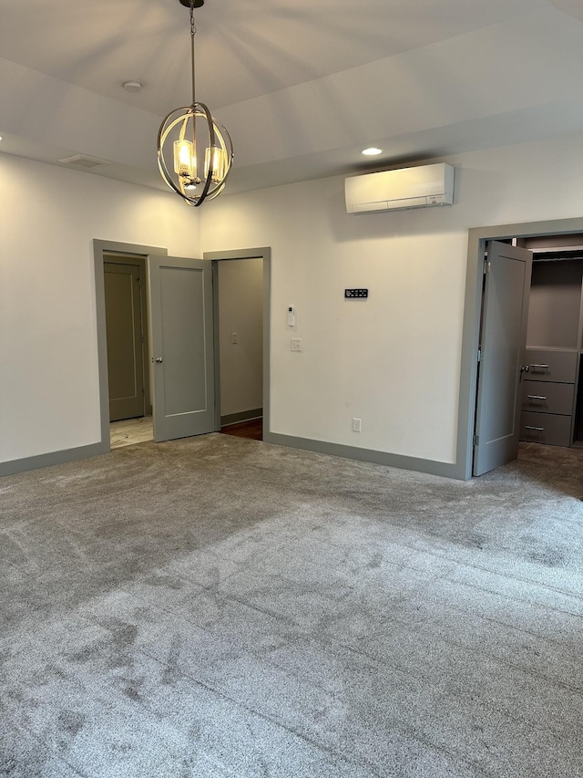 carpeted spare room featuring a wall mounted AC, a chandelier, and baseboards